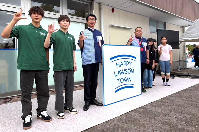 フォトセッションで「Lマーク」のポーズをとる、左から人間社会学科2年倉重陽さん、高木我聞さん、株式会社ローソン　代表取締役 社長 竹増貞信氏