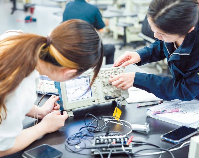 測定装置の数値を確認する学生
