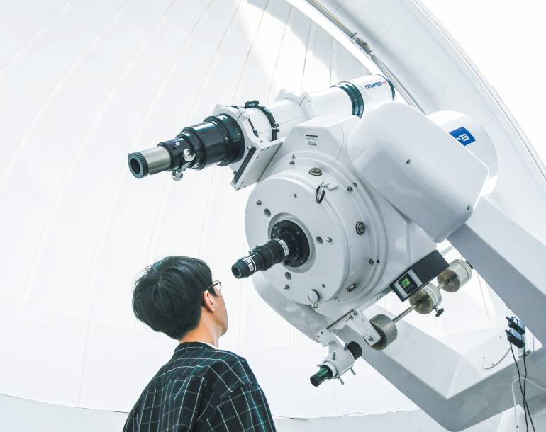 天文台で天体観測をする学生